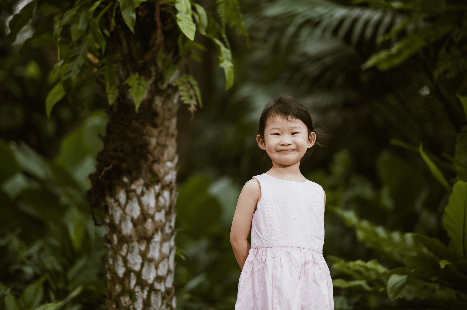 smiling girl posing in front of lush tree