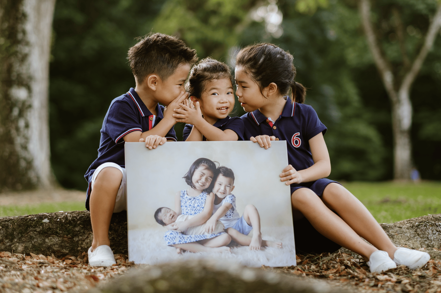 kids holding a portrait of their younger selves